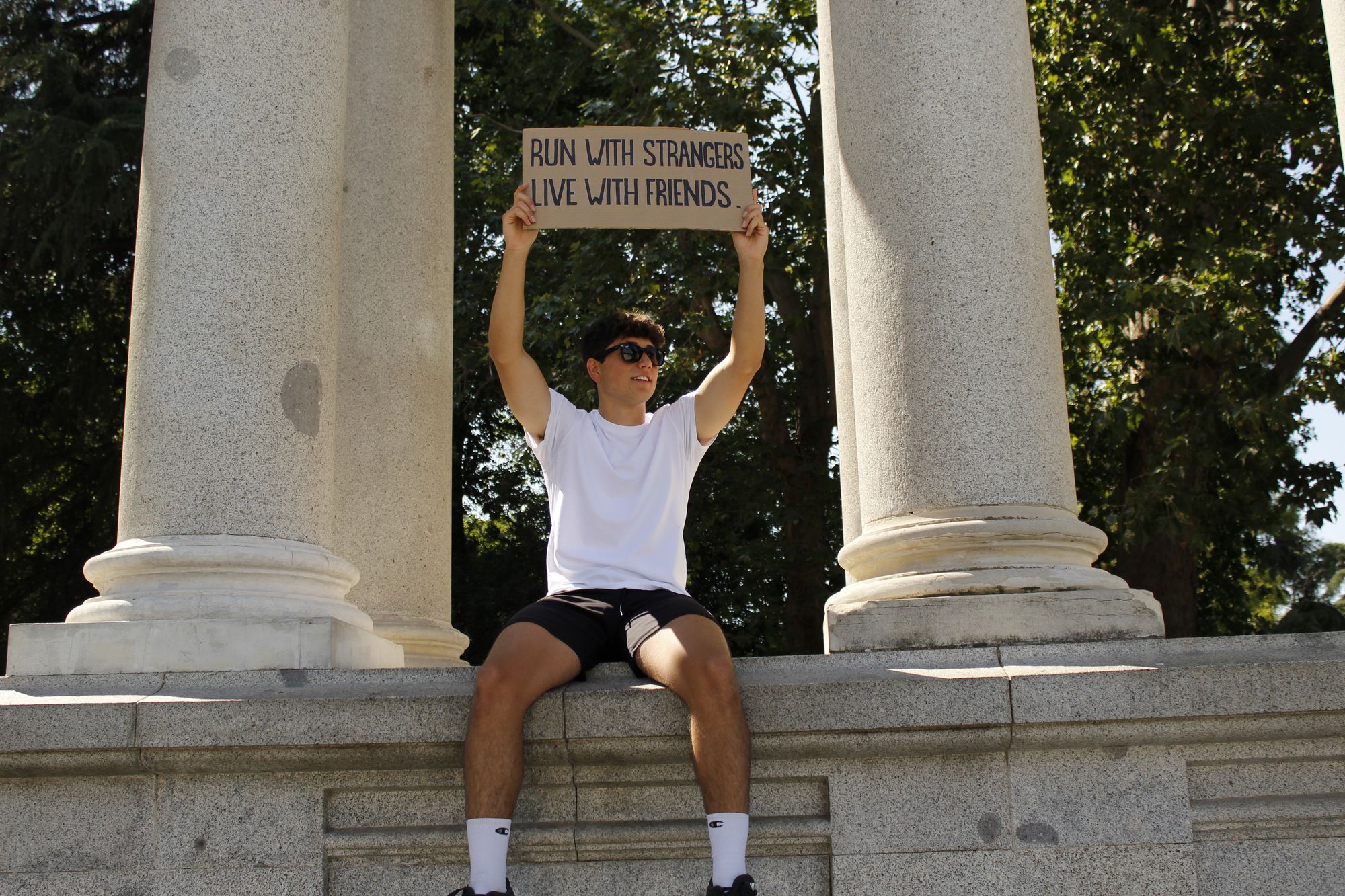 Miembro de Inner Club en la columnata del Retiro sosteniendo el cartel del evento