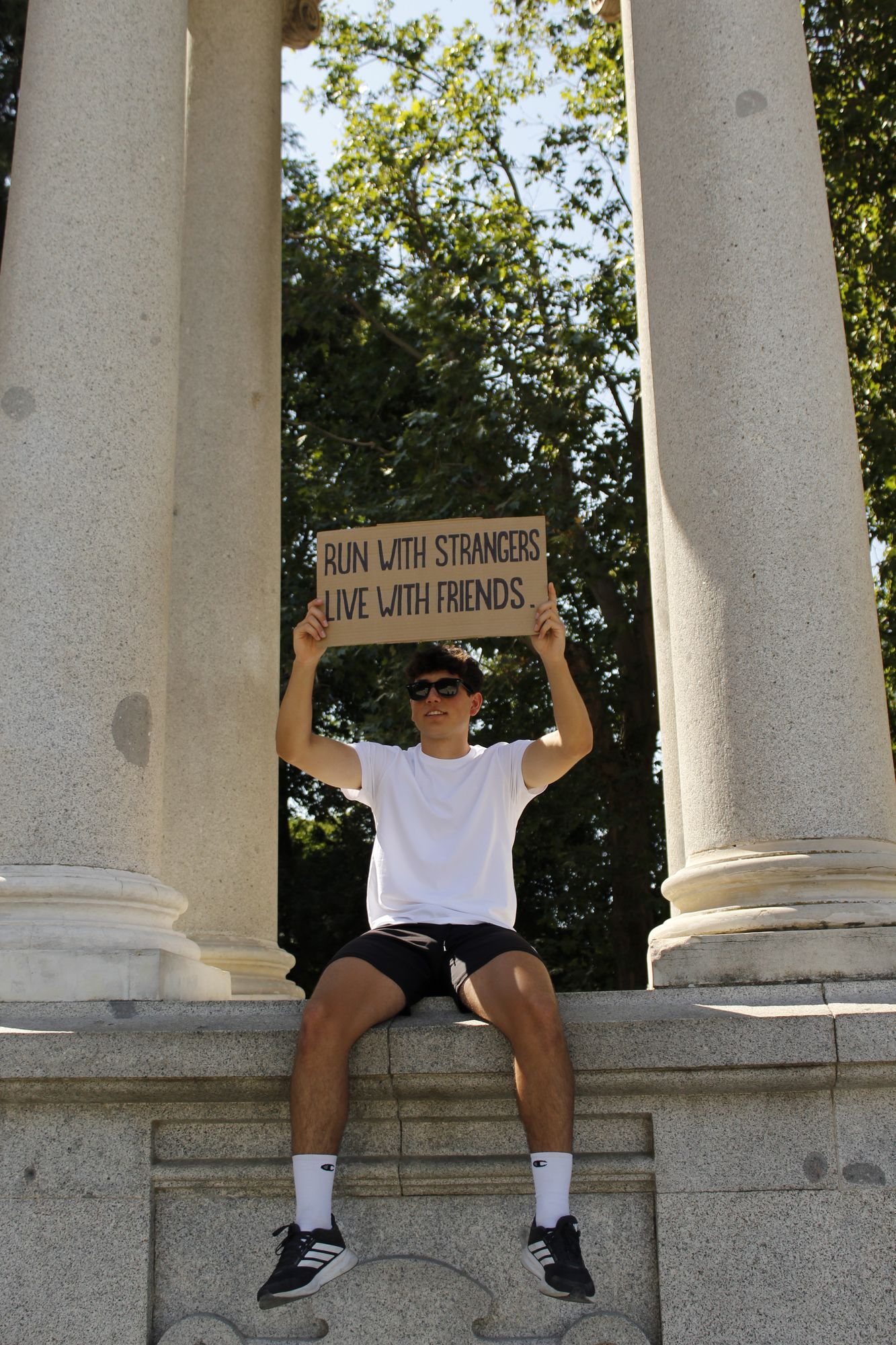 Miembro de Inner Club sosteniendo el cartel Run with strangers, live with friends a contraluz